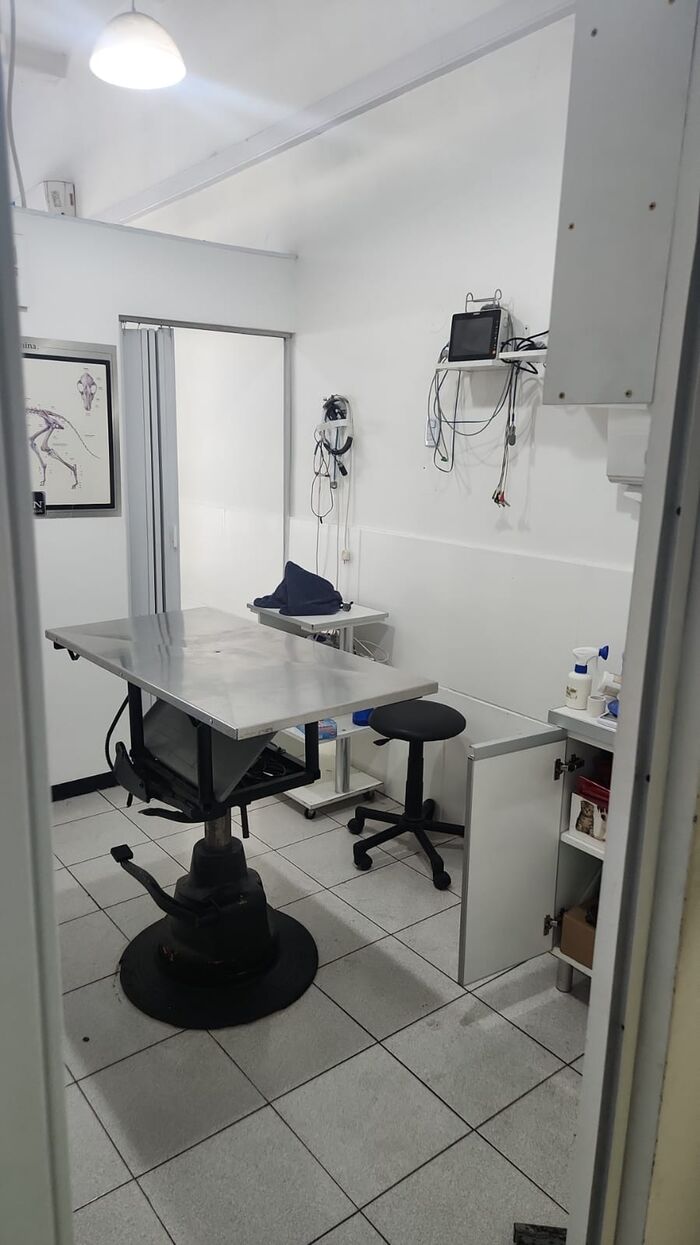 Mesa de examinación de acero inoxidable en el consultorio, con equipamiento en la pared